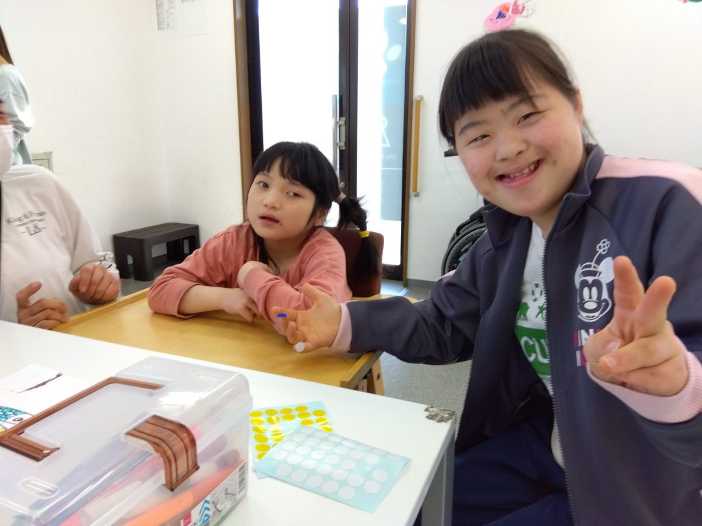 埼玉県所沢市の放課後等デイサービス、児童発達支援事業所オハナピース新所沢でお友達と共に笑顔で写真に写っている様子
