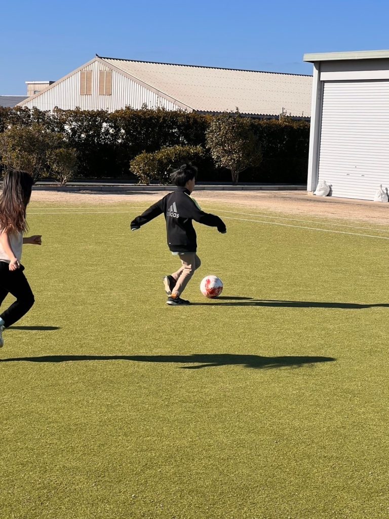 オハナピース花園町、スカイランドHARADAの芝生でサッカーをする児童
